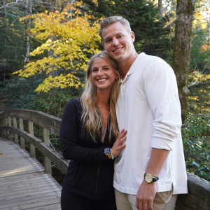 Team member and partner pose outside in a park.